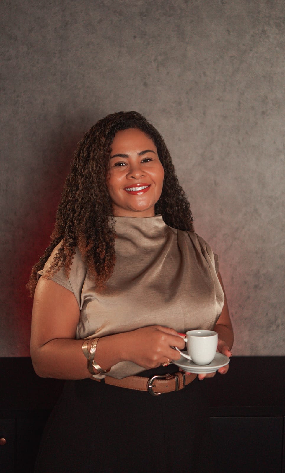 Dra. Marcela Paixão sorrindo com xícara de café, transmitindo acolhimento no atendimento ao cliente